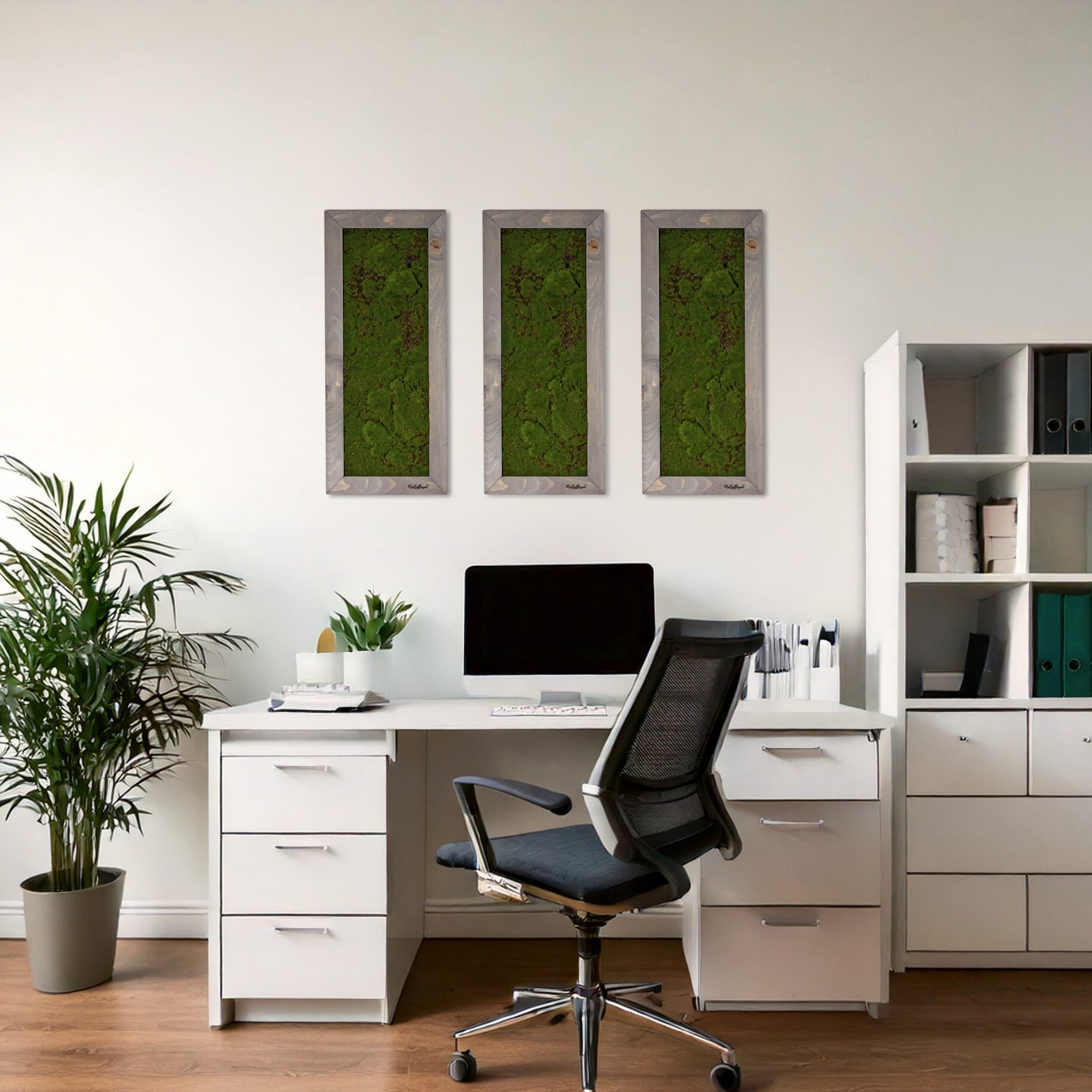 Drei vertikale Moosbilder als natürliche Wanddekoration, über einem weißen Schreibtisch in einem modernen Homeoffice.