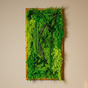 Langformatiges Greendecors Pflanzenbild mit dichten Farnen und künstlichen Ranken an einer beigefarbenen Wand, kombiniert mit Sofa, Tischlampe und modernem Beistelltisch