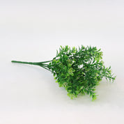 Künstlicher Grünzweig mit kleinen grünen Blättern und feinen weißen Blüten auf weißem Hintergrund, dekorative Kunstpflanze für Wohnraumdeko und Interior-Styling.