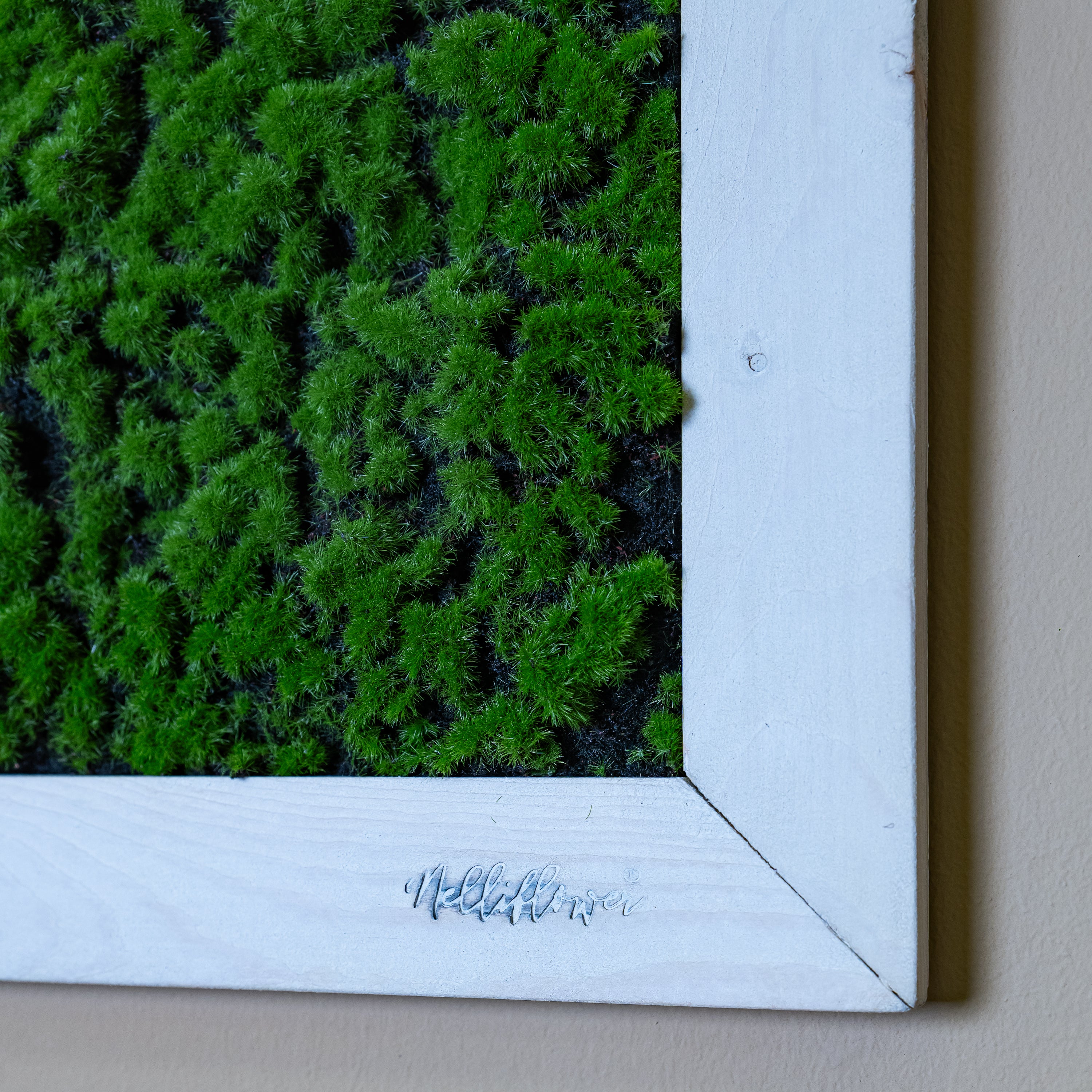 Nahaufnahme künstl. Moosbild mit Logo in weißen Holzrahmen