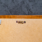 Rückseite eines Holzrahmens mit MDF-Platte und mittig montierter Zackenaufhängung vor einer dunklen Strukturwand