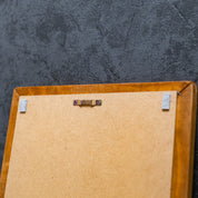 Rückseite eines Holzrahmens mit MDF-Platte und mittig montierter Zackenaufhängung vor einer dunklen Strukturwand